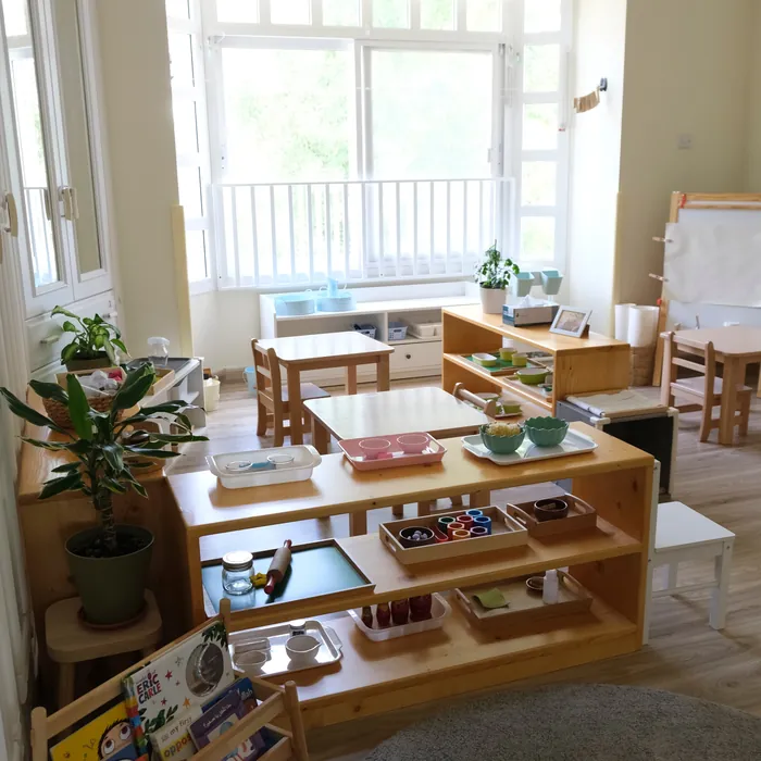A bright classroom with low wooden shelves by the window