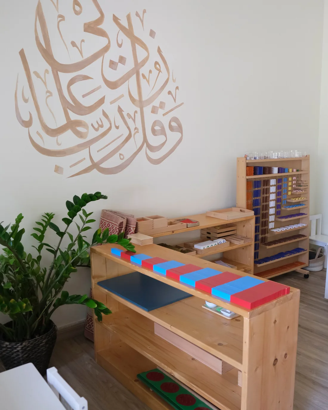 Arabic calligraphy on the classroom wall beside natural wooden Montessori materials