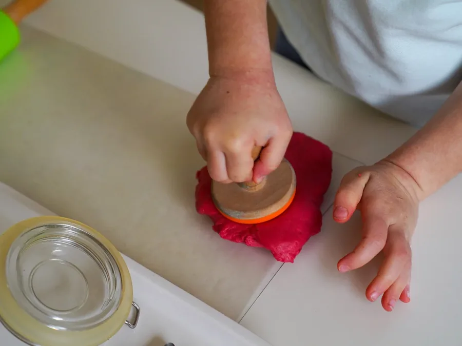 A child shaping material with their hands at a Montessori practical-life table