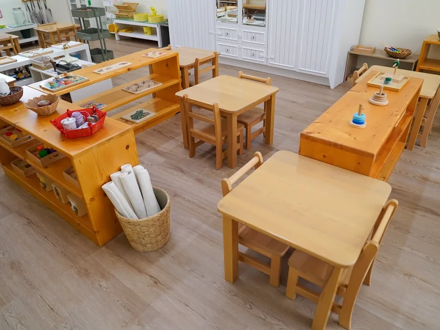 A Montessori classroom with low wooden tables and child-height shelves